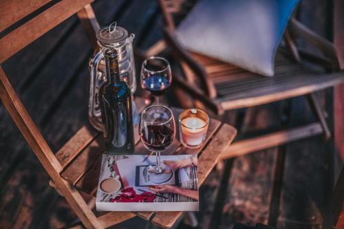 a table with two glasses of wine and a bottle at Koliba Šume Pjevaju - robinzonski smjestaj, struja 12 V, voda iz cisterne in Mrkopalj