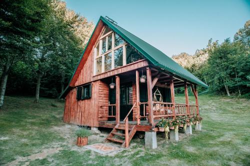 a large wooden cabin with a green roof at Koliba Šume Pjevaju - robinzonski smjestaj, struja 12 V, voda iz cisterne in Mrkopalj