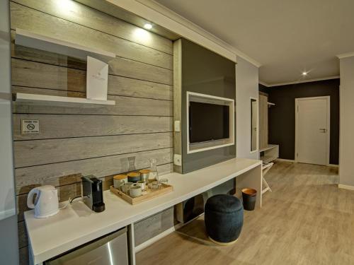a bathroom with a sink and a tv on a wall at Atlantic Garden Boutique Hotel in Swakopmund