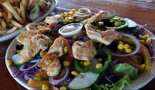 a plate of food with a salad with corn and vegetables at Rainbow Hotel in Caye Caulker