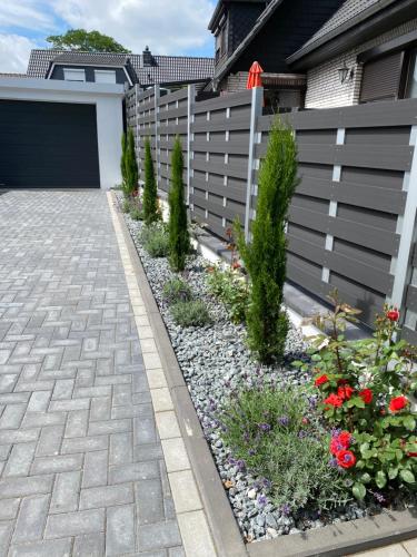 a fence with a garden of flowers next to a driveway at Luxuriöses Ferienhaus Anita nahe Timmendorfer Strand, Travemünde und Lübeck in Sereetz