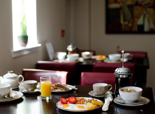 a table with plates of food and cups of orange juice at The Park Guest House in Aviemore