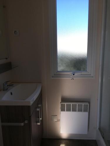 uma casa de banho com um lavatório e uma janela em Mobilhome avec vue sur étang em Bec-de-Mortagne