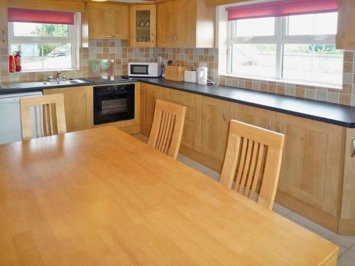 eine große Küche mit einem Holztisch und Stühlen in der Unterkunft Timmys Cottage Heir Island by Trident Holiday Homes in Skibbereen