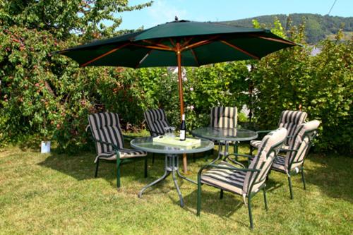 uma mesa com quatro cadeiras e um guarda-sol em Weingut Bollig-Prüm em Trittenheim