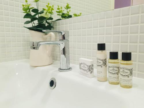 a sink with three bottles of soap and a faucet at Stay in Apartments Ribeira 24 in Porto