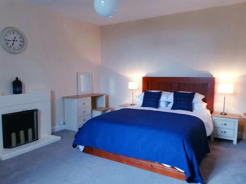 a bedroom with a blue bed and a fireplace at Benside Cottage in Stornoway
