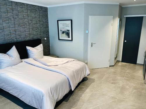 een slaapkamer met een groot bed met witte lakens bij OLÉ Hotel in Hamburg
