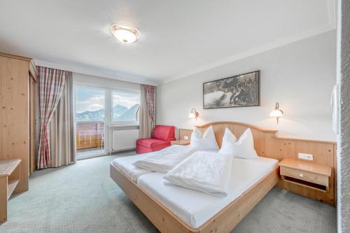 a hotel room with a bed and a red chair at Gasthof und Hotel Rieder GmbH in Jenbach