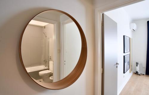 uma casa de banho com um espelho redondo na parede em Spot Apartments no Porto