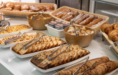 a buffet filled with different types of bread and pastries at Hotel Rosamar Maxim 4*- Adults Only in Lloret de Mar