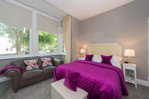 - une chambre avec un lit violet et un canapé dans l'établissement Albany House by Harrogate Serviced Apartments, à Harrogate