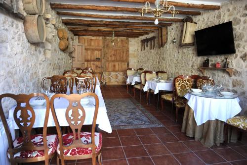 a dining room with tables and chairs and a tv at Hotel Rural El Labrador in San Pedro de Gaíllos