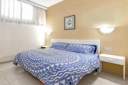 a bedroom with a blue and white bed and a window at Altamira Apartamentos Adeje in Adeje