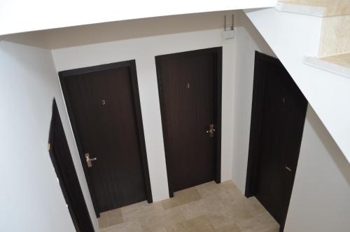 a hallway with three black doors on a wall at White Hotel in K'obulet'i