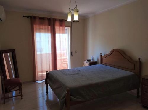 a bedroom with a bed and a chair and a window at Beija Flor in Monte Gordo