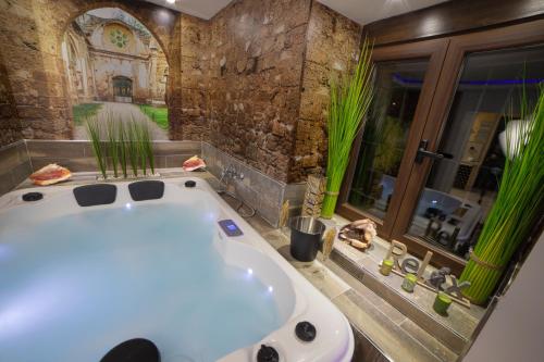 a bath tub in a bathroom with a stone wall at LA VEGUILLA DELUXE JACUZZi in Alhama de Aragón