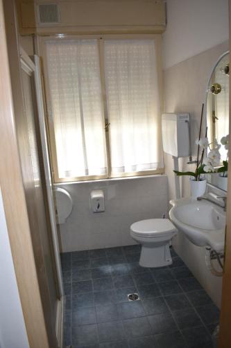 La salle de bains est pourvue de toilettes, d'un lavabo et d'une fenêtre. dans l'établissement Villa Emma, à Nago-Torbole