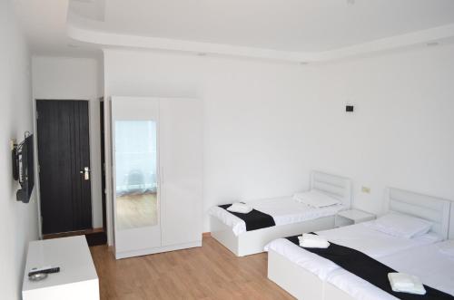a white bedroom with two beds and a mirror at White Hotel in K'obulet'i