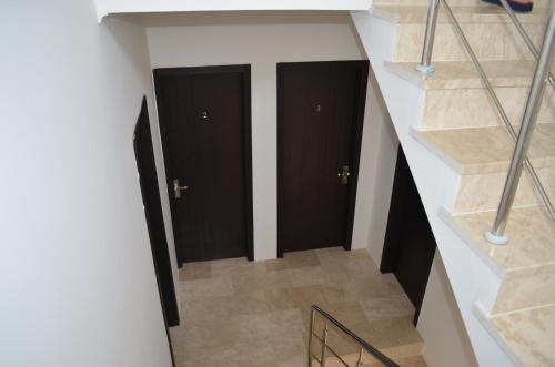 a hallway with two black doors and stairs at White Hotel in K'obulet'i