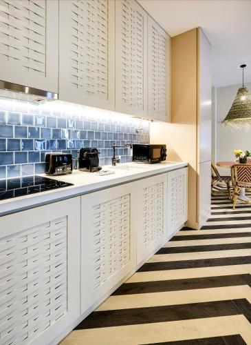 a kitchen with white cabinets and blue tiles at Vila na Praia Foz Luxury Apartments in Porto