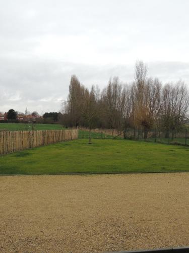 a green field with a fence and trees at "De VRIJBOS ROUTE" alleenstaande dubbele woning! in Kortemark