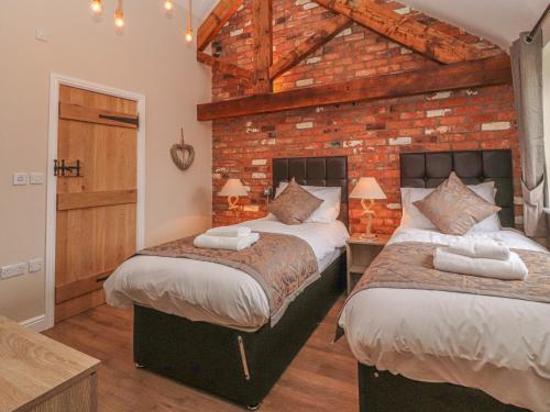 a bedroom with two beds and a brick wall at The Shippon in Chester