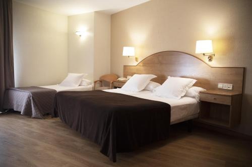 a hotel room with two beds and two tables at Hotel Maruxia *** Superior in O Grove