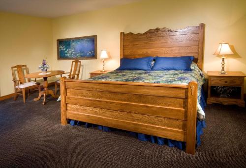 a bedroom with a large wooden bed and a table at Carlisle Inn in Sugarcreek