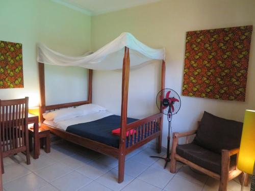a bedroom with a canopy bed and a chair at Bikeventures House Uganda in Jinja