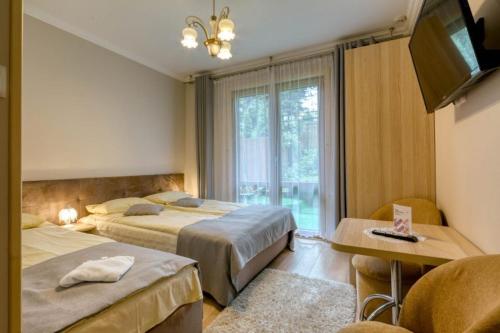 ザコパネにあるPokoje Gościnne Dawidekのベッド2台とテレビが備わるホテルルームです。