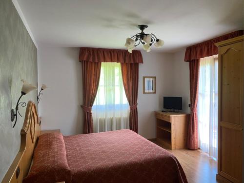 1 dormitorio con cama, TV y cortinas en Villa Golf, en Pinzolo