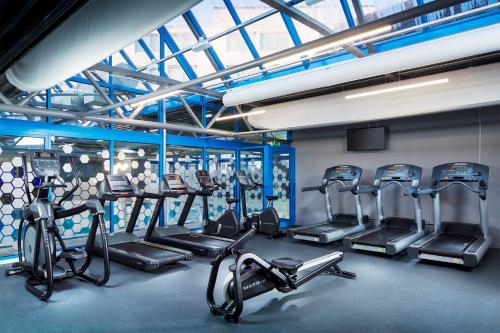a gym with several treadmills and cardio machines at Radisson Hotel and Conference Centre London Heathrow in Hillingdon