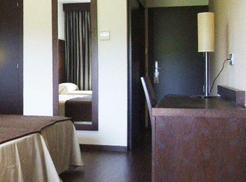 a room with a bed and a dresser and a mirror at Complejo Leo 24H in Monesterio