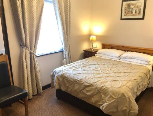 a bedroom with a bed and a window and a chair at Atlantic Guest House in Donegal