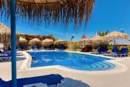 uma piscina com cadeiras e guarda-sóis de palha em Soulis Hotel em Oia
