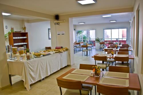 a restaurant with tables and chairs with food on a buffet at Hotel Jardin De Iguazu in Puerto Iguazú