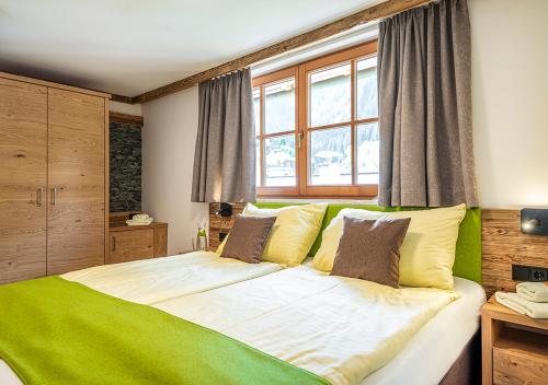 a bedroom with a green and white bed with a window at AlpinSpa zur Post - Bergbahn im Sommer 2025 inklusive in Bad Gastein