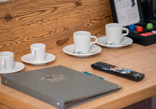 a desk with a laptop and cups and a remote control at AlpinSpa zur Post - Bergbahn im Sommer 2025 inklusive in Bad Gastein
