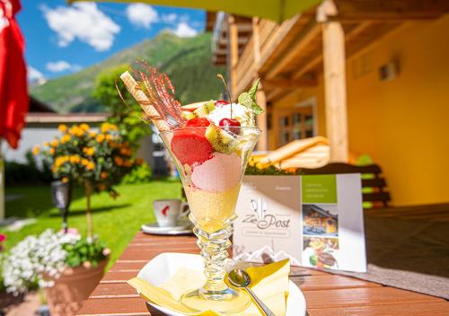 a drink with fruit in a glass on a table at AlpinSpa zur Post - Bergbahn im Sommer 2025 inklusive in Bad Gastein