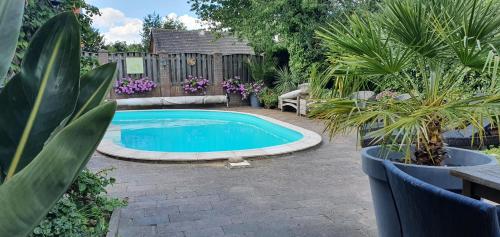 a swimming pool in a garden with plants and a fence at B&B Knooppunt70 in Arcen