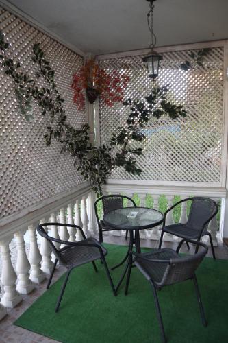 a table and four chairs on a porch with a green rug at Sobe-Apartmani Modriča in Modriča