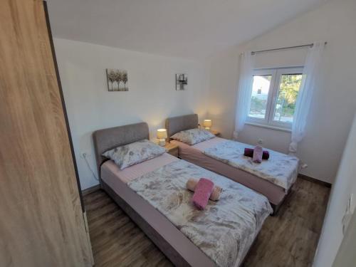 two beds in a small room with a window at Apartmani Goga 2 in Molat