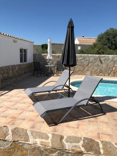 two lounge chairs and an umbrella next to a pool at Casa Olivia villa in Arboleas