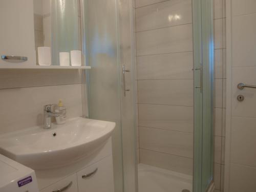 a white bathroom with a sink and a shower at Apartmani Goga 2 in Molat