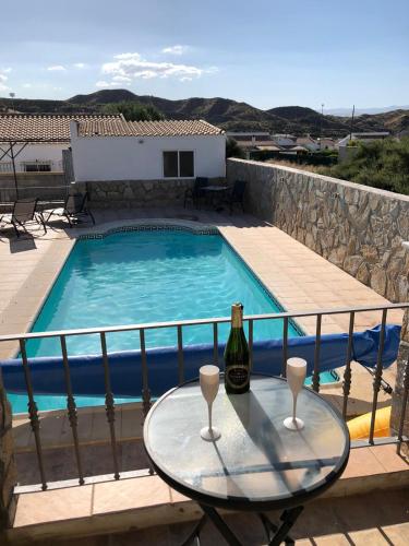 a bottle of wine on a table next to a swimming pool at Casa Olivia villa in Arboleas