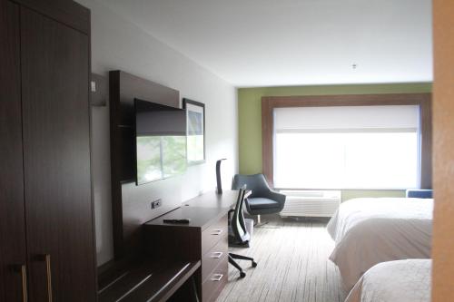 a bedroom with a desk and a bed and a television at Holiday Inn Express & Suites - Kokomo South by IHG in Kokomo