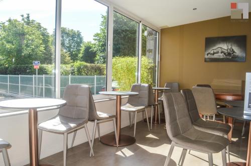 - une salle d'attente avec des tables, des chaises et des fenêtres dans l'établissement Hôtel Le Printemps, à Saint-Georges-de-Didonne