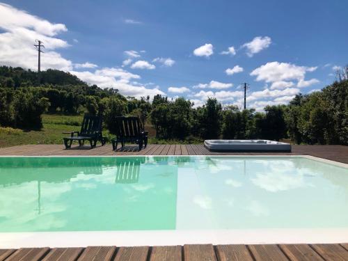 two chairs sitting next to a swimming pool at Quinta dos Sabores Farm Houses in Ribeira Grande