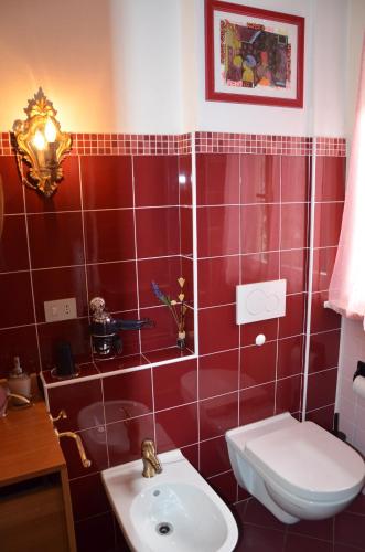 a red tiled bathroom with a toilet and a sink at B&B Villa Olmo in Como